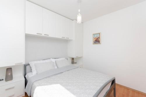 a white bedroom with a bed and white cabinets at Apartments Dujo in Rupe