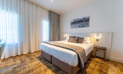 a bedroom with a bed and a large window at The Grosvenor Hotel in Timaru