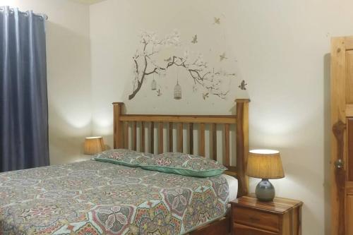 um quarto com uma cama e um mural de árvore na parede em Chrisanns Hidden Cove 2 bedroom em St Mary