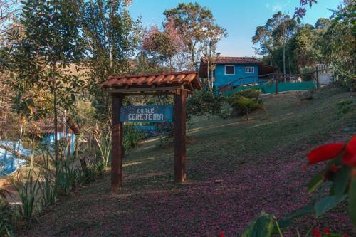 a sign for a garden with a house in the background at Chalés Cerejeira in Visconde De Maua