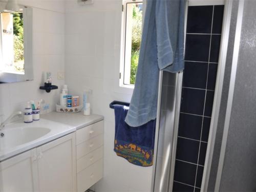 La salle de bains est pourvue d'un lavabo et d'une douche avec une serviette bleue. dans l'établissement Maison plain-pied avec jardin, à 350m de la plage, WIFI, à Pleumeur-Bodou - FR-1-368-358, à Pleumeur-Bodou