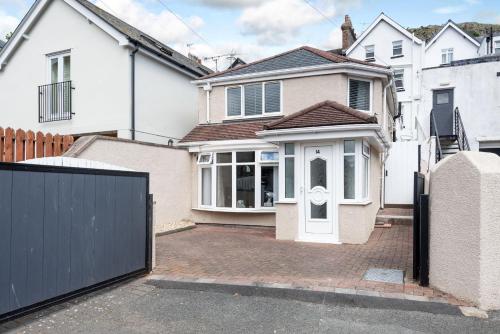 a white house with a gate and a driveway at 14 Tudno Street in Llandudno
