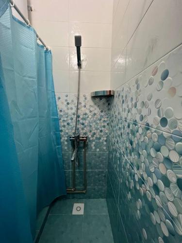 a bathroom with a shower with a blue shower curtain at Tan Nuru Guest House Гостевой Дом Тан Нуру in Cholpon-Ata