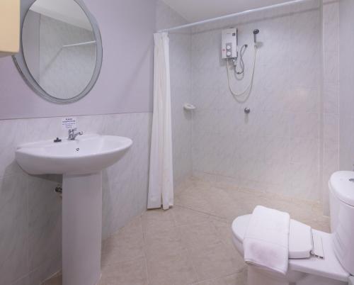 een badkamer met een wastafel, een toilet en een spiegel bij Robin's Nest Guesthouse & Restaurant in Pattaya