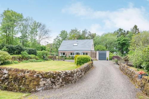 a house with a stone wall in front of a yard at Falla Farmhouse in Jedburgh