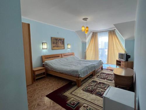 a bedroom with a bed and a desk and a television at Tan Nuru Guest House Гостевой Дом Тан Нуру in Cholpon-Ata