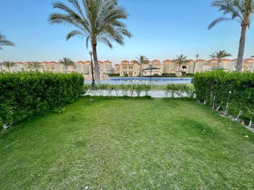a yard with palm trees and a swimming pool at Stella Heights villa - next to Marassi - North coast in El Alamein