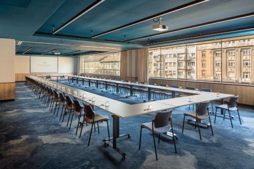 a long table with chairs in a room with large windows at Crowne Plaza Budapest by IHG in Budapest