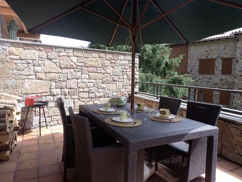 una mesa con sillas y una sombrilla en el patio en Can Vilà- Vall de Camprodon, en Vilallonga de Ter