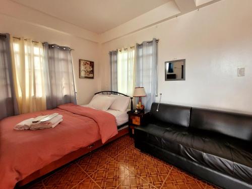 ANDY'S PLACE في ليغاسبي: غرفة نوم مع سرير وأريكة جلدية سوداء