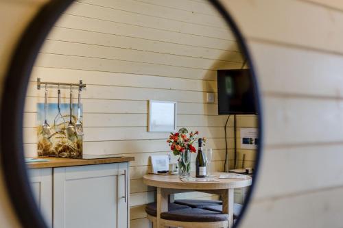 a mirror reflecting a kitchen with a table with flowers at Corndon Pod in Shrewsbury