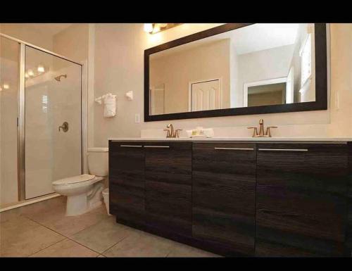 a bathroom with a toilet and a sink and a mirror at SPACIOUS 6bdrm Villa near ALL the attractions!! in Haines City