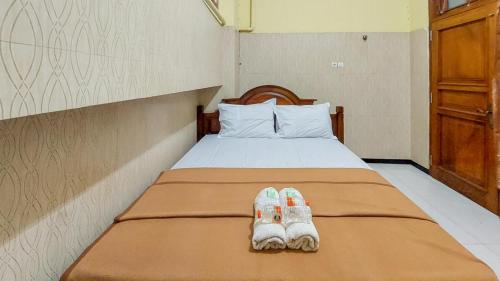dwie pary kapci siedzą na łóżku w obiekcie Hotel Shinta 2 near Alun Alun Kertosono Mitra RedDoorz w mieście Pelem
