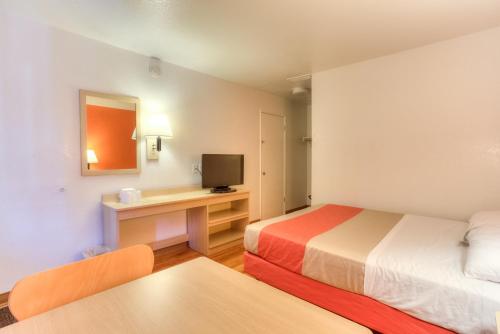 a room with two beds and a desk with a television at Motel 6-Tigard, OR - Portland South - Lake Oswego in Tigard