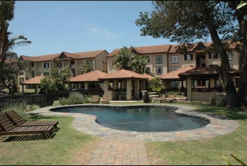 una piscina en un patio con bancos y un edificio en 35 on Bondi South Africa, en Shelly Beach