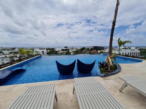 a large swimming pool with two hammocks on top of a building at Modernos Estudios a pasos De La 5ta Av Pool view - By Yeah in Playa del Carmen