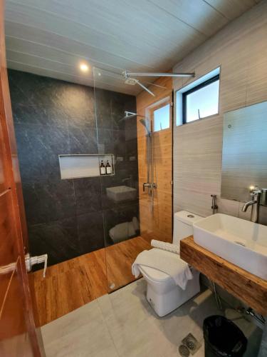 a bathroom with a toilet and a sink and a shower at Balar Hotel and Spa in Boac