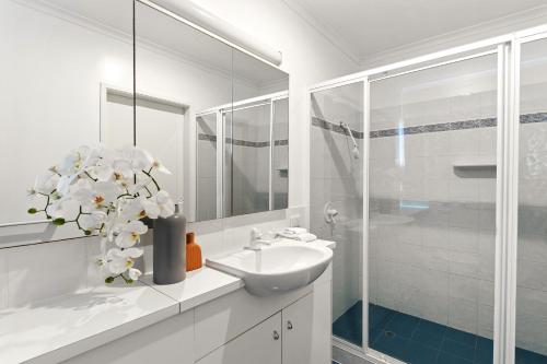 ein weißes Badezimmer mit Waschbecken und Spiegel in der Unterkunft Noosa Riverfront Splendour, Ideal for Families in Noosa Heads