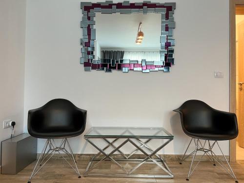two black chairs and a glass table in front of a mirror at Apartament Popescu in Călimăneşti