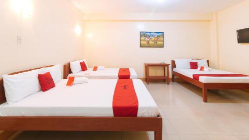 a room with two beds with red and white sheets at RedDoorz @ Golden Park Inn La Union in Lossoc