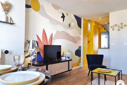 a living room with a table and chairs and a tv at The Four Seasons - Panoramic View - Niemeyer Volcano View in Le Havre