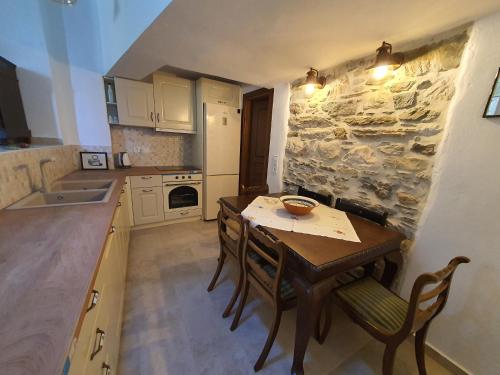 a kitchen with a table and chairs and a stone wall at PYRGOS - Traditional house at Kaloxilos, Naxos in Khalkíon