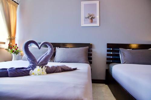 two beds with a stuffed animal in the shape of a heart at GOLDEN GUESTHOUSE by The Beach Cha Am in Cha Am