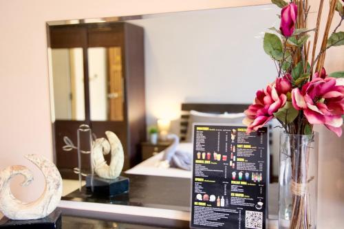 a vase filled with pink flowers on a counter with a mirror at GOLDEN GUESTHOUSE by The Beach Cha Am in Cha Am