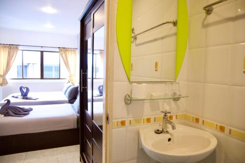 a bathroom with a sink and a bedroom with two beds at GOLDEN GUESTHOUSE by The Beach Cha Am in Cha Am