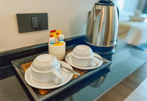 two cups and saucers on a counter in a kitchen at Grand Lord Hotel & Residence - Khao chi chan Pattaya in Na Jomtien