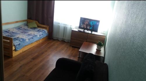 a bedroom with a bed and a table and a tv at SauleS in Ventspils