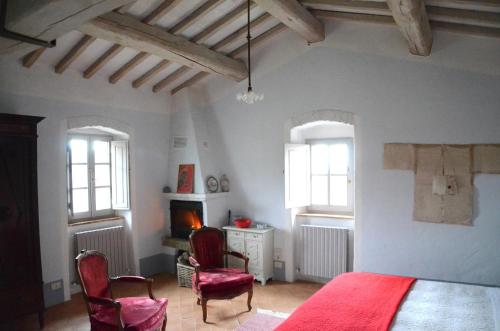 a bedroom with a red bed and two chairs at Country house Grencaia in Chianciano Terme
