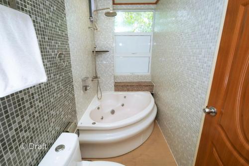 a bathroom with a tub and a toilet and a sink at Beach Breeze and Spa in Hulhumale