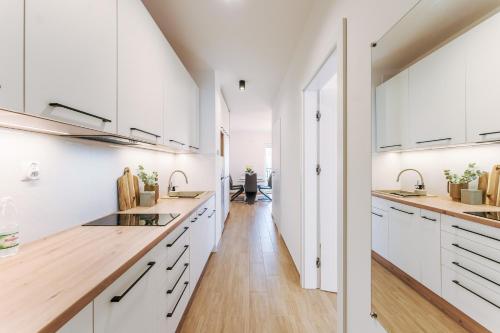 uma cozinha com armários brancos e piso em madeira em Visit Baltic Apartament Łąkowa 20 em Sarbinowo