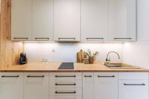 a kitchen with white cabinets and a sink at Visit Baltic Apartament Łąkowa 20 in Sarbinowo