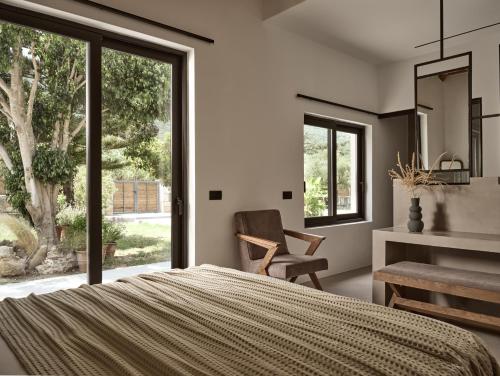 een slaapkamer met een bed, een stoel en een raam bij Yliessa - Luxury pool villa surrounded by nature in Dhrákas