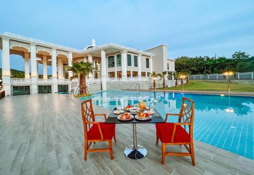 a table with food on it in front of a pool at Grand Lord Hotel & Residence - Khao chi chan Pattaya in Na Jomtien