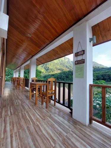 a dining room with a table and chairs on a balcony at Nam ou view villa in Nongkhiaw