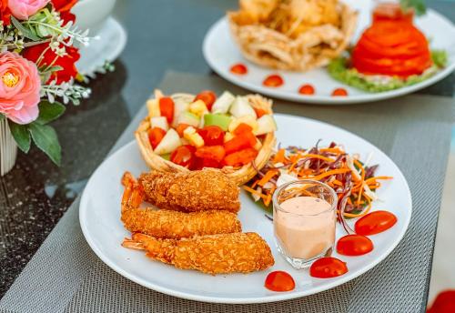 two plates of food on a table with food at Grand Lord Hotel & Residence - Khao chi chan Pattaya in Na Jomtien