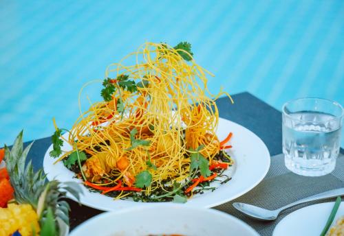 a plate of spaghetti on a table with a glass of water at Grand Lord Hotel & Residence - Khao chi chan Pattaya in Na Jomtien