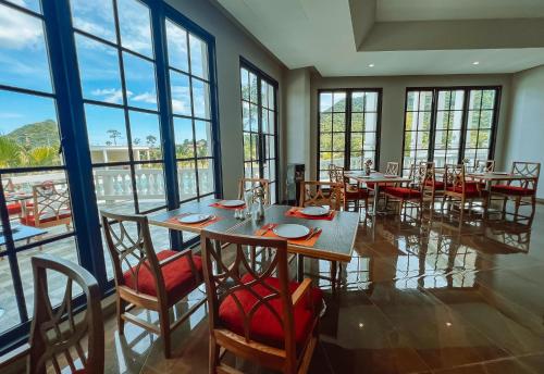 a dining room with tables and chairs and windows at Grand Lord Hotel & Residence - Khao chi chan Pattaya in Na Jomtien