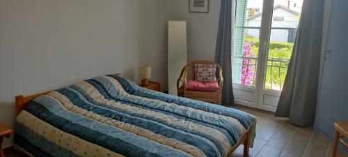 een slaapkamer met een bed, een stoel en een raam bij Le Gabian, duplex proche plage et centre in Sanary-sur-Mer