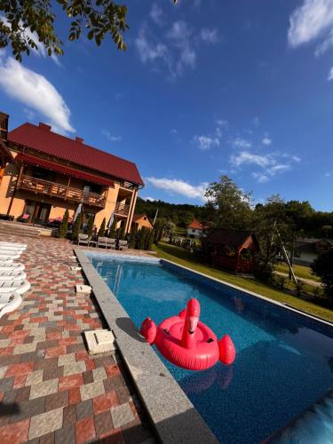 a swimming pool with a red raft in the water at Купецький Двір in Mizhhirʼʼya