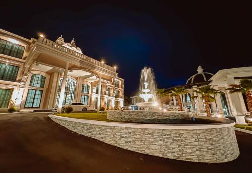 a large building with a fountain in front of it at night at Grand Lord Hotel & Residence - Khao chi chan Pattaya in Na Jomtien