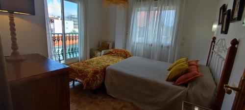 1 dormitorio con 2 camas y balcón en Pisos Vistalegre 2A con jardín tranquilos cerca del mar, en Sanxenxo