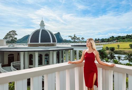 a woman in a red dress standing on a white railing at Grand Lord Hotel & Residence - Khao chi chan Pattaya in Na Jomtien