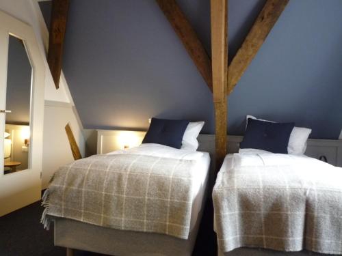 two beds in a room with blue walls and wooden beams at Hohes Haus in Greetsiel