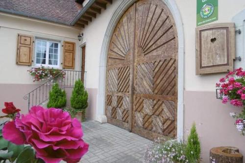 une grande porte en bois sur une maison fleurie dans l'établissement Gites les cocottes, à Zellwiller