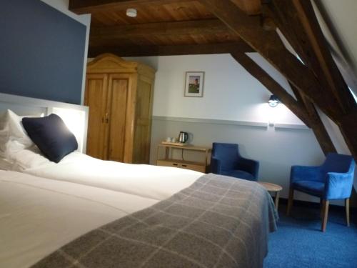 a bedroom with a bed and two blue chairs at Hohes Haus in Greetsiel