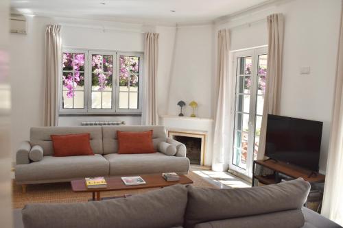 a living room with a couch and a television at Beach house upscale villa with pool in Costa da Caparica